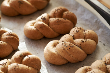Homemade braided bread buns made from whole grain spelt flour on a baking sheet