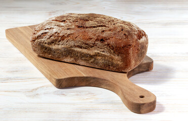 Freshly baked dark Lithuanian bread on a board on a white wooden background