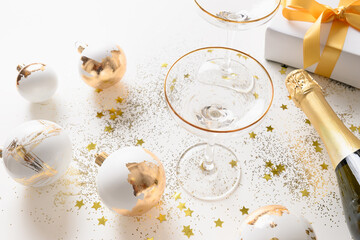 Christmas white composition with gift, shiny gold balls, champagne bottle on white background. Happy New Year greeting card.