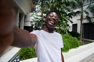 POV selfie outside of a cheerful smiling young African American man. Happy people looking at camera