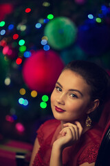 Close-up, beautiful portrait of a young girl with a festive make-up against the background of New Year's lights in bokeh