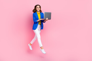 Full size photo of cheerful excited girl jumping use wireless netbook empty space ad isolated on pink color background