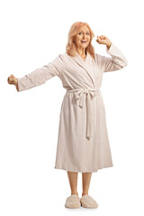 Full lenght shot of a mature woman in a bathrobe stretching and yawning