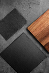 slate cutting boards on a dark stone background with wooden cutting board