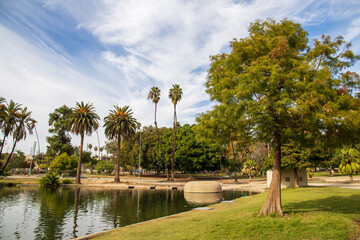 a gorgeous autumn landscape at Lincoln Park with a lake surrounded by lush green palm trees and...