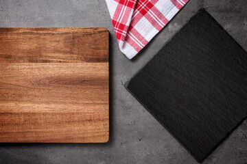 slate chopping boards on a dark stone background with wooden chopping board and red and white checkered cloth