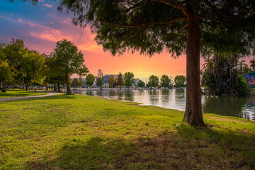 a gorgeous autumn landscape at Lincoln Park with a lake surrounded by lush green palm trees and...
