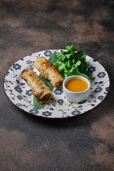  Deep-fried spring roll in rice paper served with mango sauce on a dark background