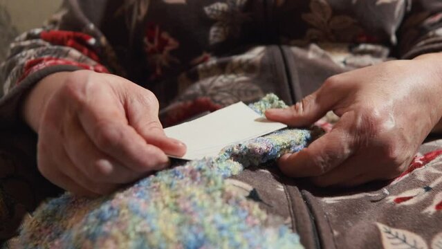 Grandma cuts out a template for New Year's socks with scissors. the active old age of the grandmother makes socks for her grandchildren with her own hands. hands of an elderly woman cutting out close-