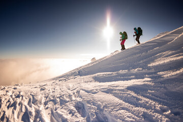 two girls with a backpack and snowshoes walk in the snow during a snow storm.