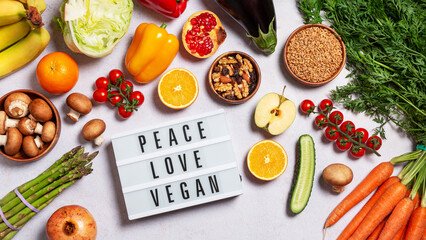 Lightbox with quote Peace, Love, Vegan on table with raw vegan foods