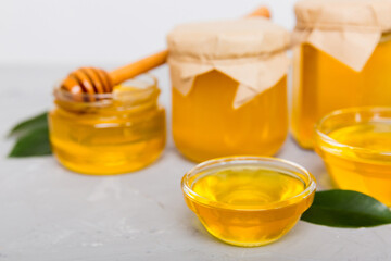 Honey in jar with leaves and honey dipper on colored background top view with copy text