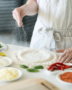 Process Of Making Pizza. Forming Pizza From Dough. Ingredients For Dough On Table. Light Background. View From Above. Soft Focus.