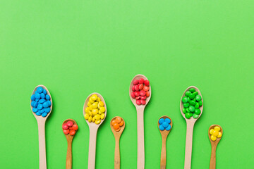 delicious colorful sweet candies on spoon on colored background . Confectionery decor top view with copy space