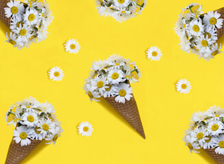 Ice cream cone with chamomiles on the yellow background. Flat lay. Pattern.