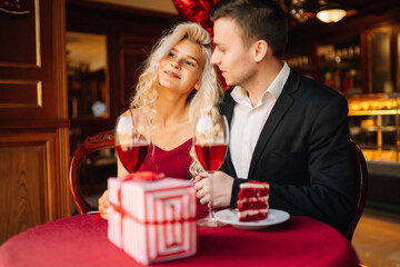 Young couple having a romantic dinner and toasting with glass of red wine. Valentine's Day concept. Relationship, surprise and love concept.
