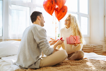 Exchange of gifts. Young couple at home celebrating Valentine's Day. Romantic day together.