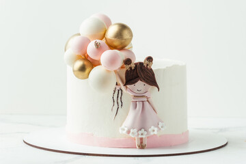 Birthday cake with white cream cheese frosting decorated with edible mastic little girl silhouette holding pink and golden balloons made of chocolate spheres. White background