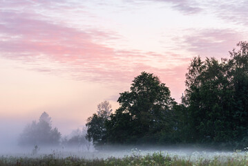 Fototapeta na wymiar Summer sunset over a foggy field. Österbotten/Pohjanmaa, Finland.