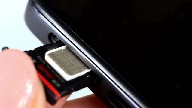 Woman hands inserting the phone sim card tray from the smartphone close up