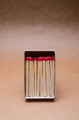 Set of new unlit matchsticks in a matchbox upright on natural brown paper background