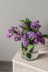 A bouquet of fresh lilacs in a glass vase top view.