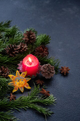 Red candle, sun amulet, cones, fir branches on dark abstract background. Witchcraft, spiritual...