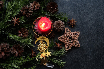 Candle, sun golden amulet, cones, fir branches on dark abstract background. Witchcraft, spiritual...