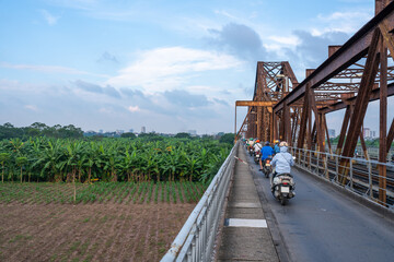 Vietnam, outside of Hanoi, scooters  drive  on  the Long Bien Bridge crossing  Banana plantations and the river. 