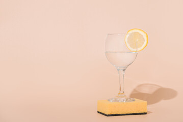 Lemon cocktail. A glass with a slice of citrus on a sponge stand for washing. Beige background.