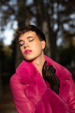 Transsexual guy with makeup standing in park with closed eyes