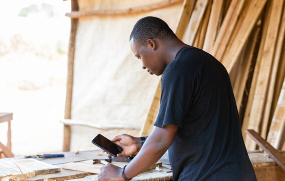 Portrait of a young professional carpenter holding a mobile phone in his hand. taking measurements using an app on their smartphone