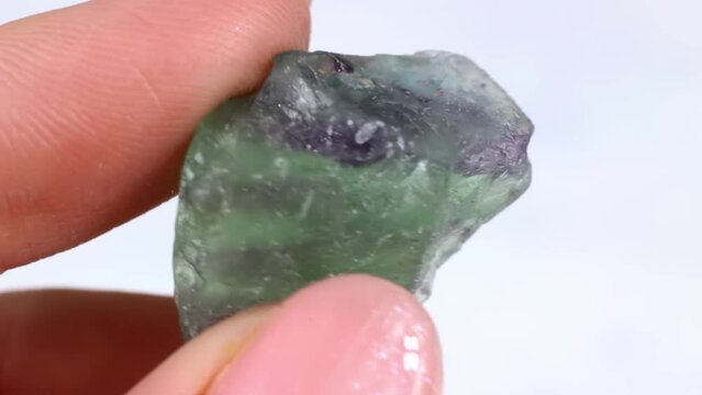 Woman hand holding green crystal Fluorite (Fluorspar) on light background close up
