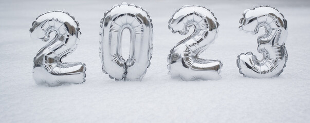 Banner with silver numbers of the New Year 2023, in winter on a background of white snow with copy space