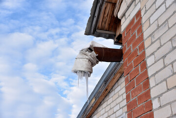 Spontaneous ventilation pipe in a house with icicles and ice in winter. The ventilation pipe is...