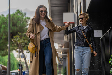 Two adult women learn to ride skateboard in a city. Urban lifestyle scene in Barcelona.