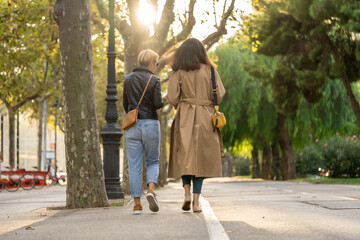 Two adults, 35s years old businesswoman with sunglasses walk from office to a town with coffee cup. Urban modern lifestyle scene of Barcelona city.