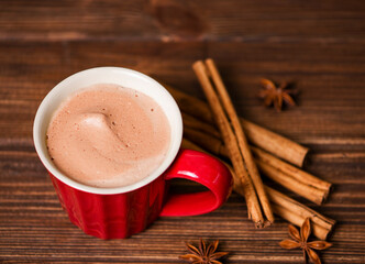 Cinnamon sticks, a cup of coffee, star anise on a wooden background