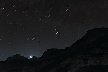 Astronomical long exposure photography of stars with star trails and the famous Saentis summit,...