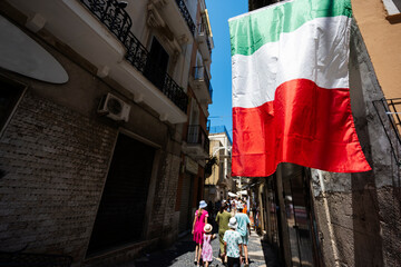 Family of tourists waking in streets Bari, Puglia, South Italy. Italian flag.