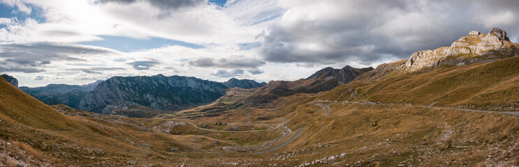 Obraz premium Mountain panorama with rocks, clouds and yellow grass