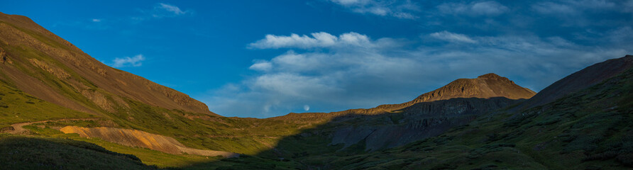 Fototapeta na wymiar Moon rising between the mountain divide at sunset, panorama