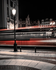 Autobús rojo dejando estela de larga exposición por la noche en Valencia.