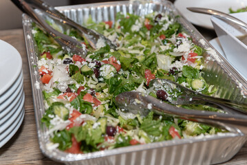 Serving dish full of green salad for the healthy conscious guests attending the party