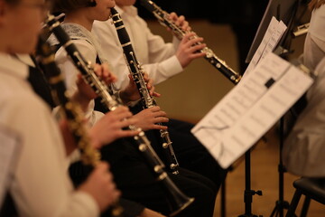 A group of young musicians with wind instruments playing in an orchestra.Background image with selective focus on a black clarinet - obrazy, fototapety, plakaty