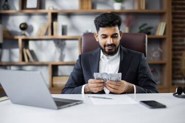 Fototapeta na wymiar Rich business man working on laptop counting money cash, calculate earnings income profit at office workplace. Professional manager freelancer guy. Business people. Employment, occupation