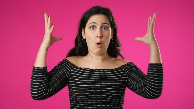 Attractive thinking young woman 20s, looks at camera gives mind blown gesture showing explosion of ideas posing on pink background.