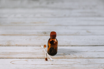 Glass special brown bottle with iodine and soft sticks for ears, hygiene close-up on a wooden background. Photography, medicine, hygiene, copy space.