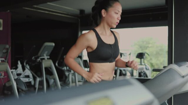 Woman having workout on treadmill at gym side view