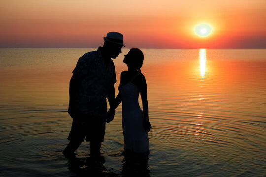 A Happy couple by the sea at sunset on travel silhouette in nature